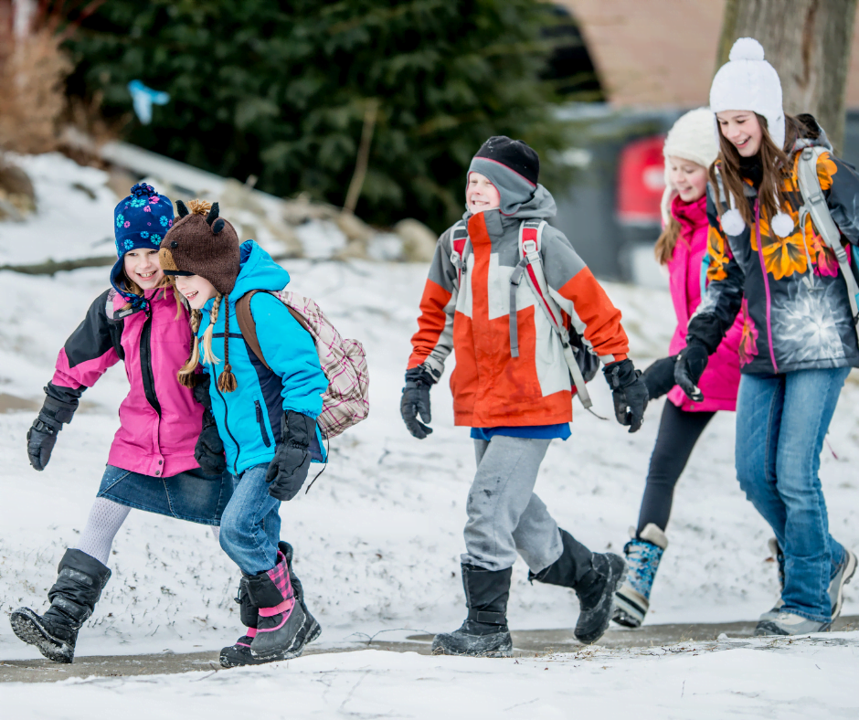 A group of children wearing backpacks walking to school during the winter. 